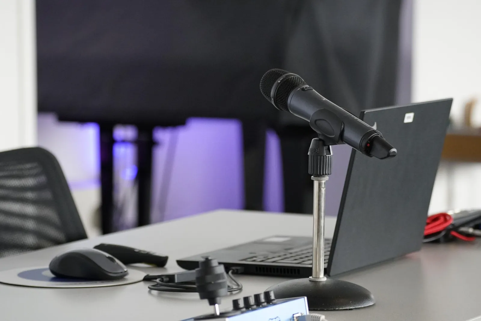 A home podcast desk setup with a microphone, mixer and laptop
