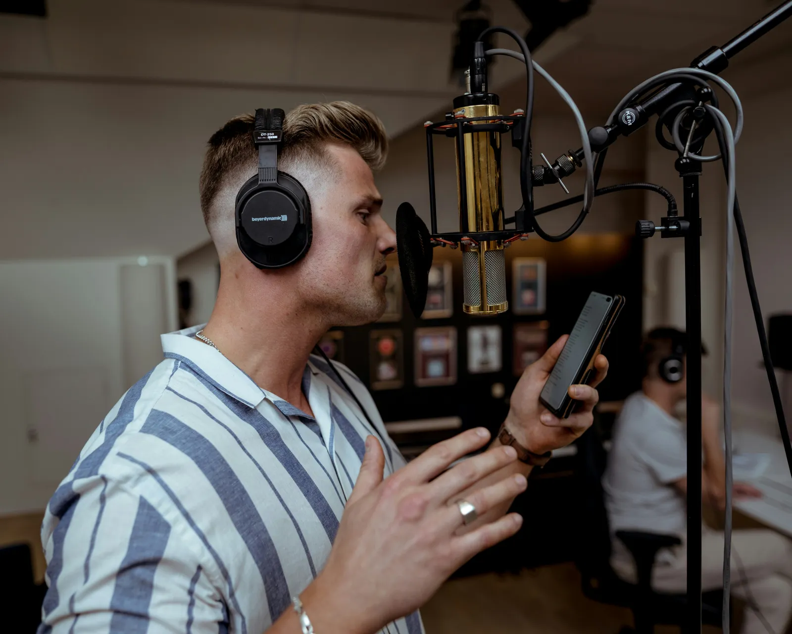 A person recording into a studio microphone wearing headphones